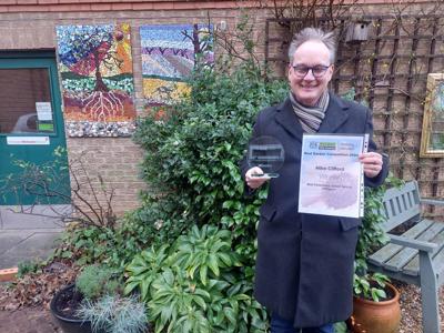 A picture of Mike Clifford holding his Best Communal green space winning trophy and certificate